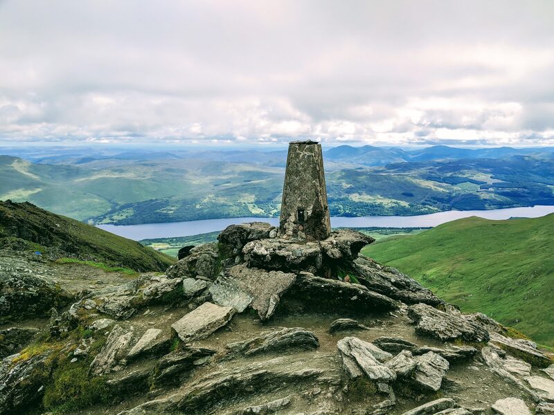 The summit pillar on its rocks with Loch Tay far below.