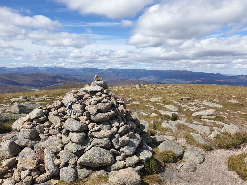 A stone cairn on the stony plateau, hills to the horizon under broken cloud.