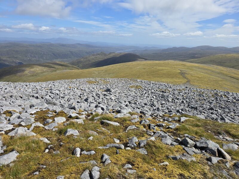 Grey boulders on the rounded top of Sgùrr na Ruaidhe, hills rolling away beyond.