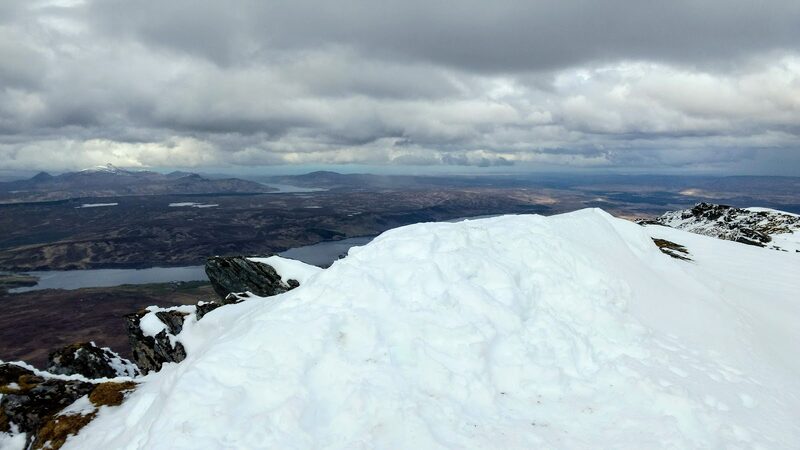 Snow banked on the top of Ben Klibreck, with lochs and empty moor running to the horizon under cloud.