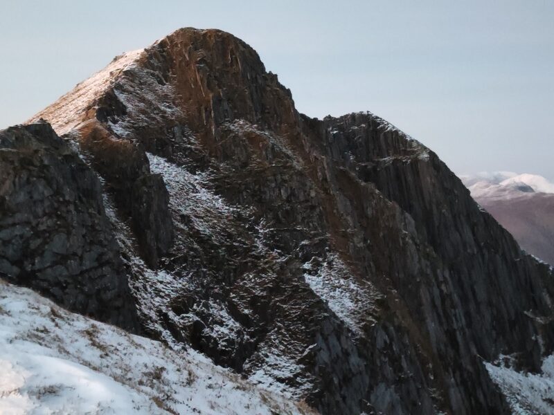 The dark crags under the top of Ciste Dhubh with a dusting of snow, in low light.