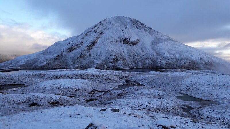 The hill's cone under snow, seen across frozen, snow-covered ground.