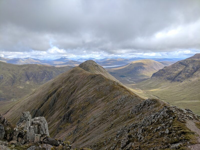 The ridge of Buachaille Etive Beag running from a rocky top to a further summit, with moor and distant hills beyond.