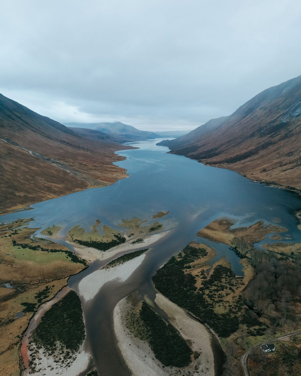 Loch Etive winding between steep mountains, a river delta in the foreground, from above.