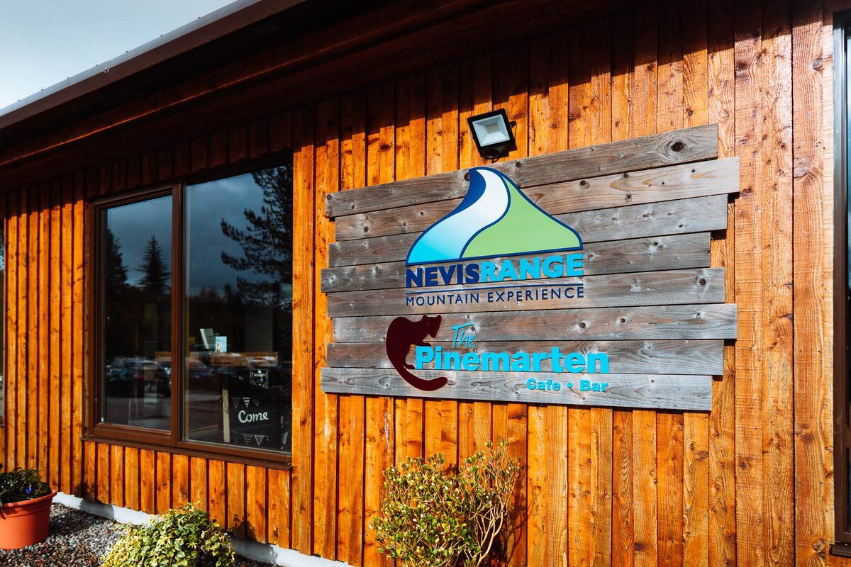 The timber base station at Nevis Range, its sign above the door and pots of flowers.