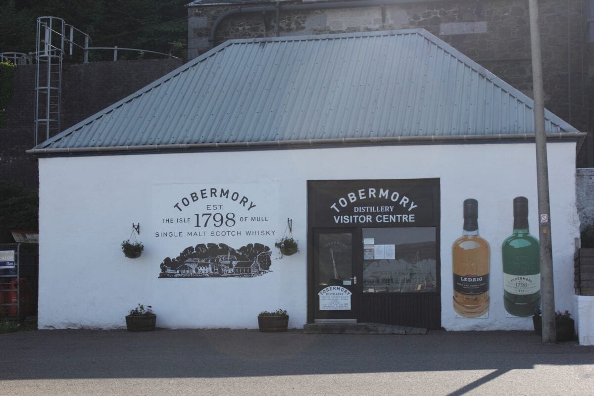 The whitewashed front of the Tobermory Distillery visitor centre, painted with the year 1798 and bottles.