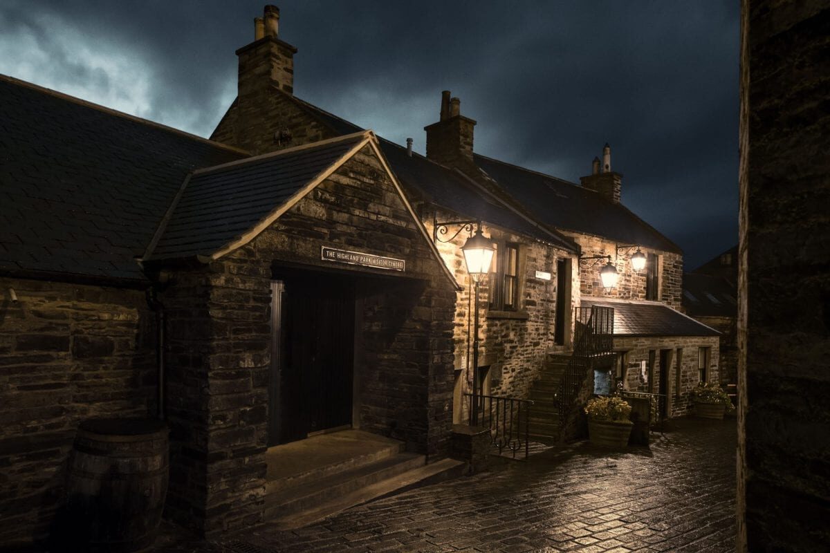 Highland Park Distillery's stone buildings and cobbled yard lit by lamps at dusk.