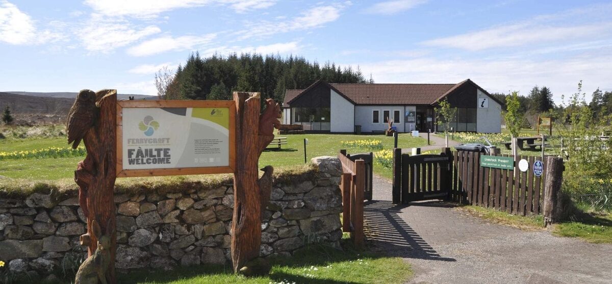 Wooden gate and "Failte Welcome" sign beside a stone wall at a visitor centre