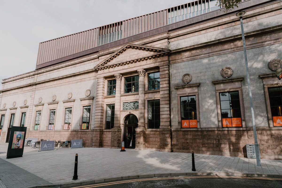 Sandstone building with columned entrance and orange window displays on street corner