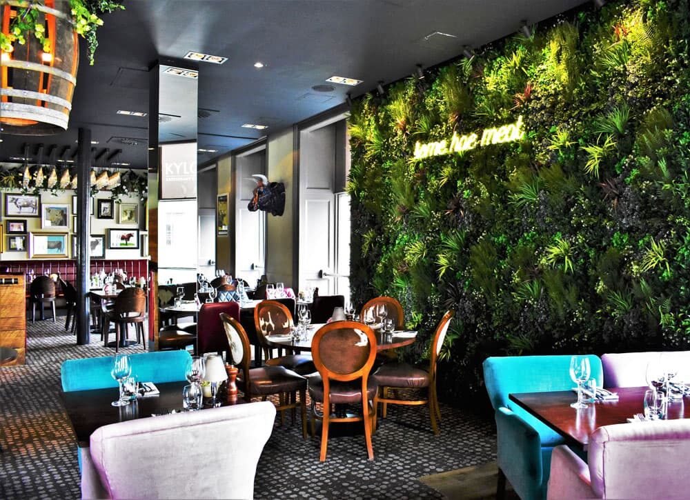 Restaurant interior with a living plant wall reading "beer, hae, meat
