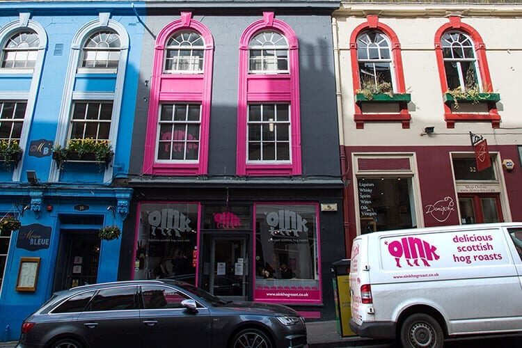 Blue, pink and grey terraced buildings above the Oink hog roast shop