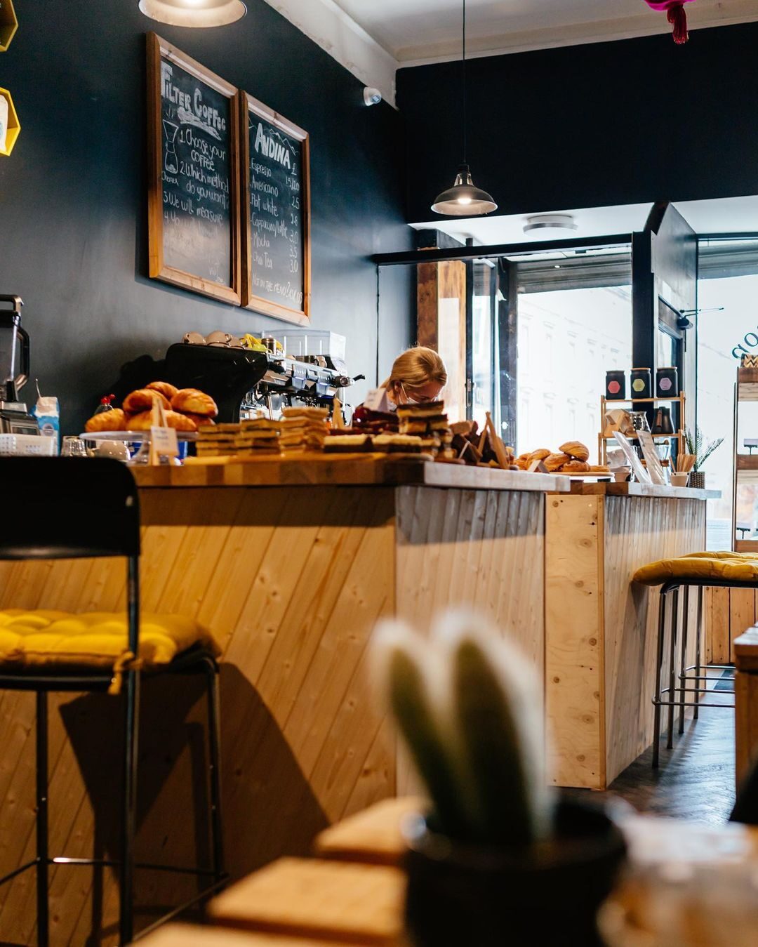 Wooden counter with pastries and chalkboard menus reading "Filter Coffee