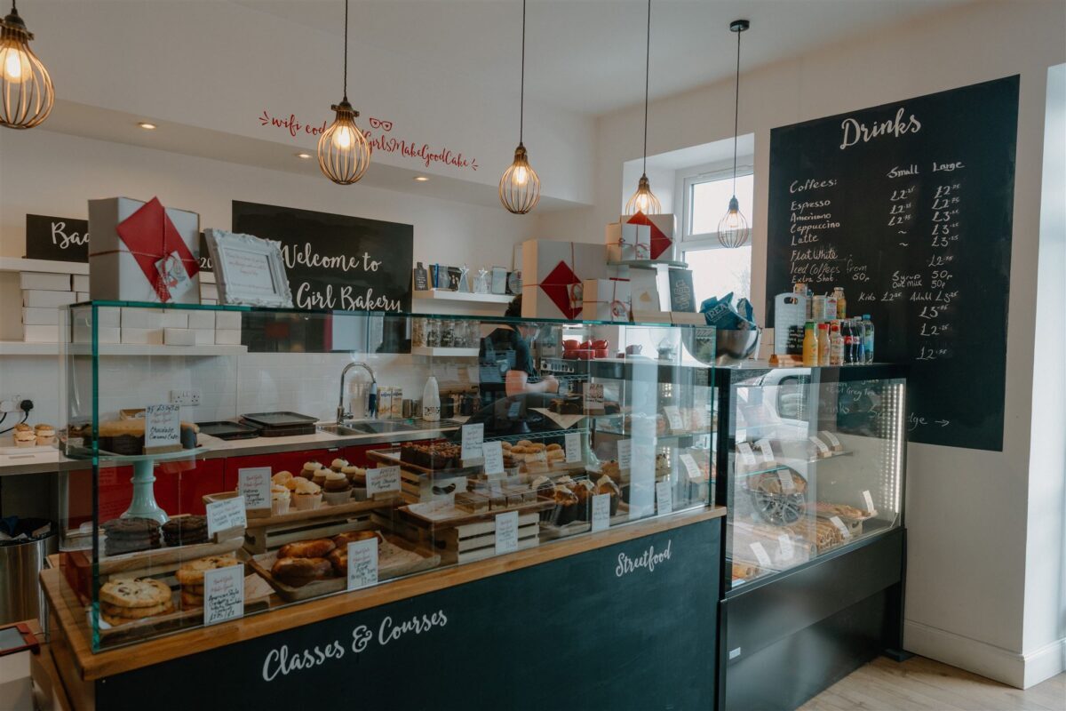 Bakery counter with pastries under glass and a chalkboard drinks menu