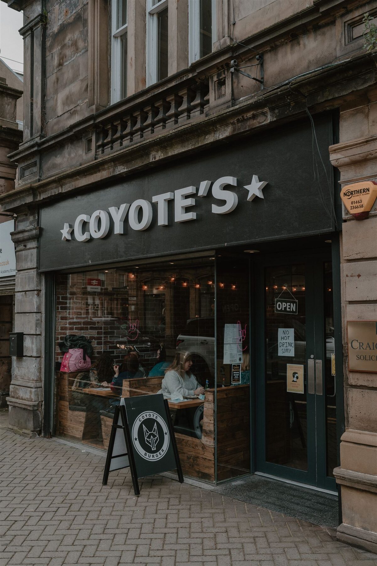 Coyote's café storefront with an Open sign and pavement blackboard