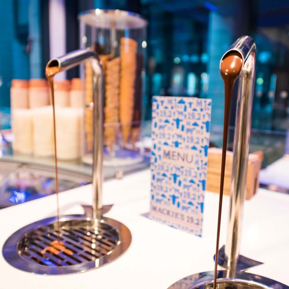 Chocolate sauce taps beside a Mackie's 19.2 menu card and cones