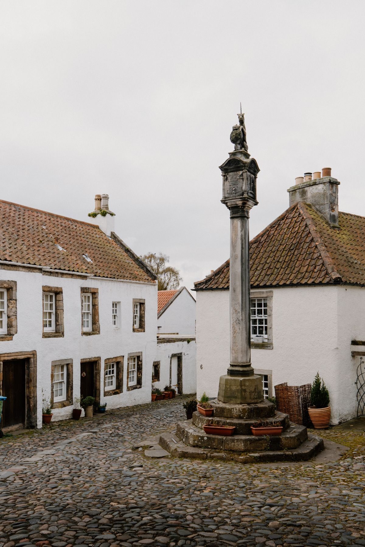 The Mercat Cross and its unicorn finial among white houses.
