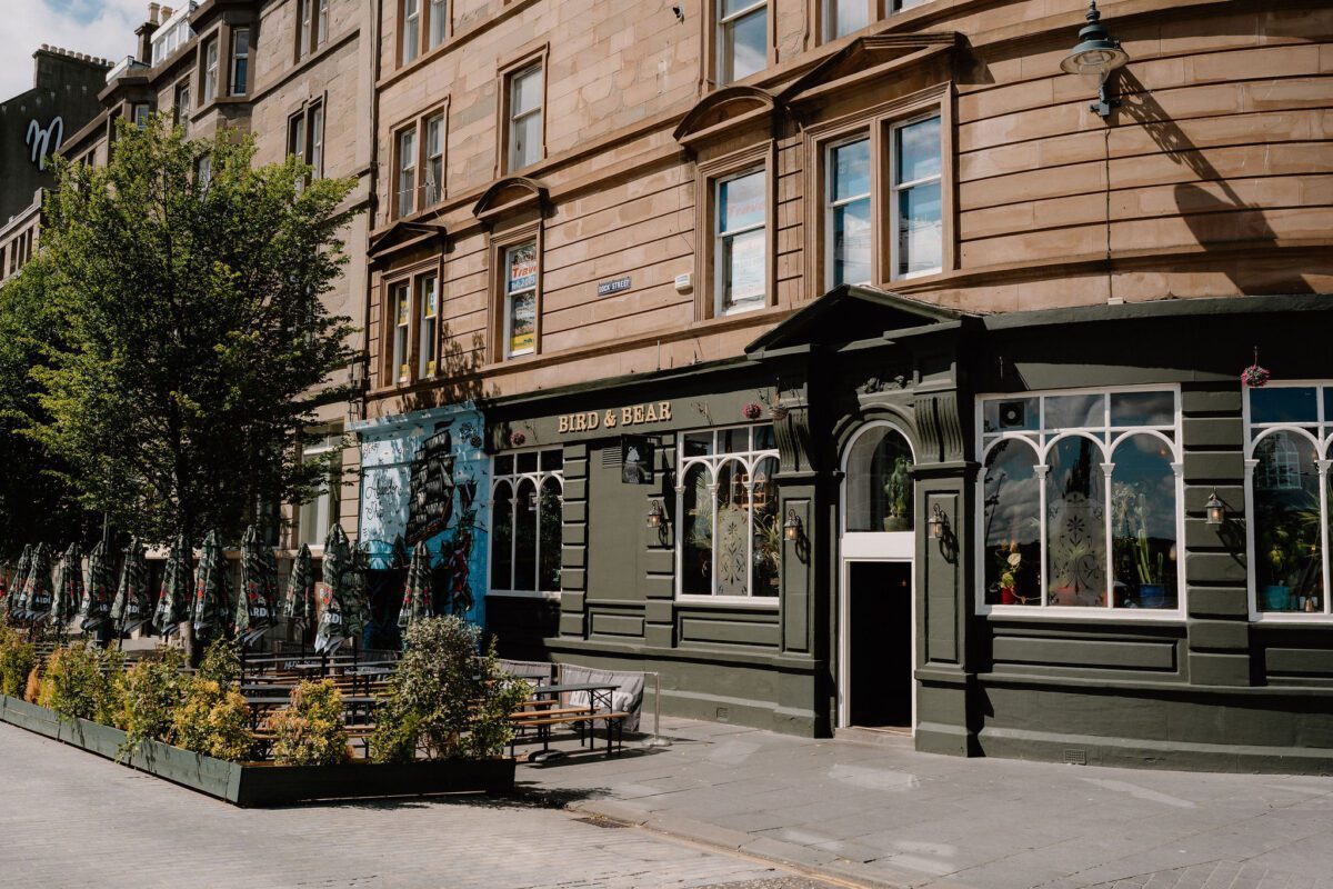 Sandstone tenement building with green-fronted corner pub below