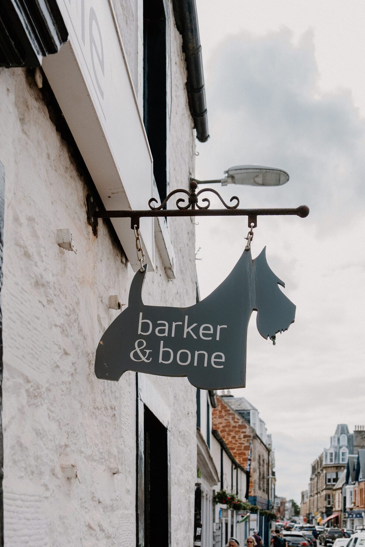Terrier-shaped "Barker & Bone" sign hanging from a whitewashed shopfront