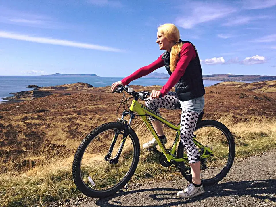 Woman on a mountain bike pauses on a coastal path overlooking the sea