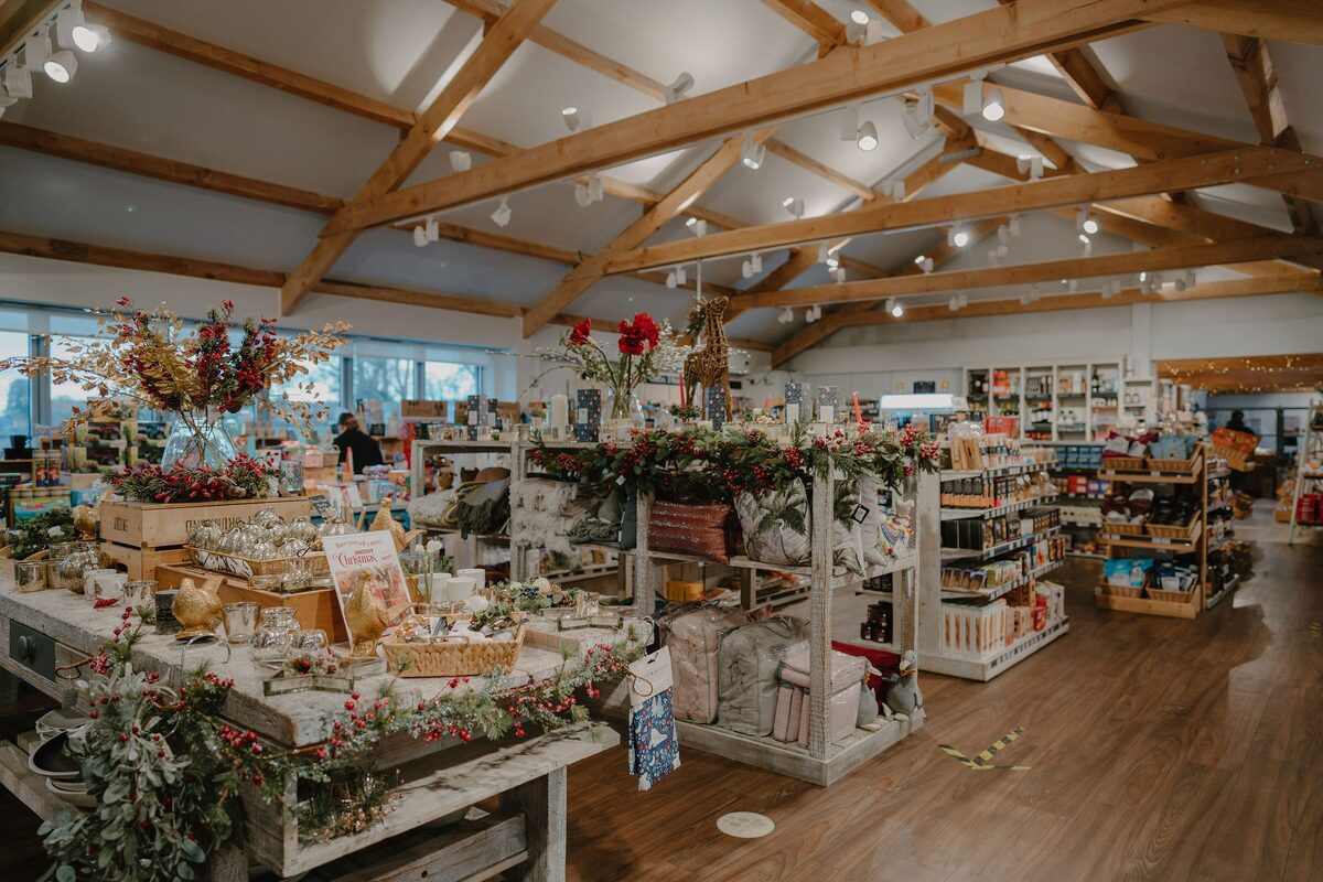 Inside the Smiddy farm shop, stalls of produce under timber roof beams.