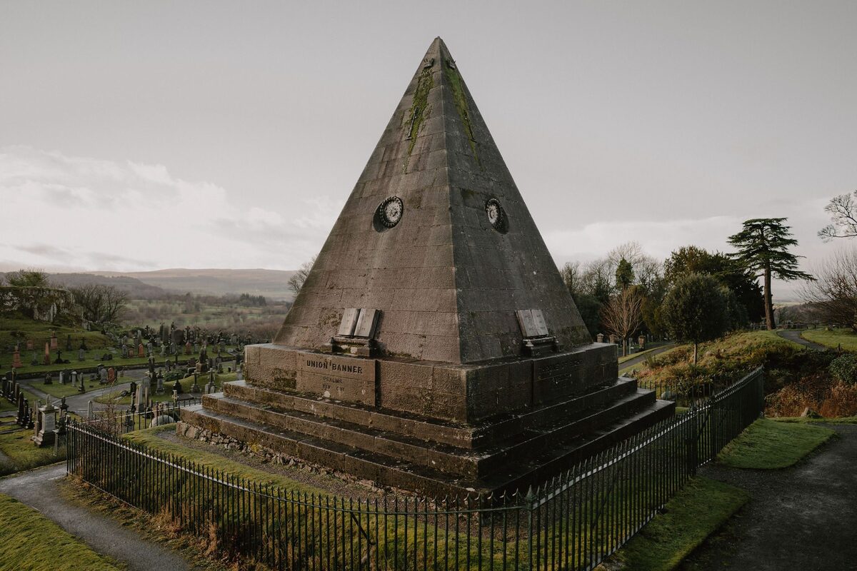 Stone pyramid monument rises above gravestones in a hillside cemetery