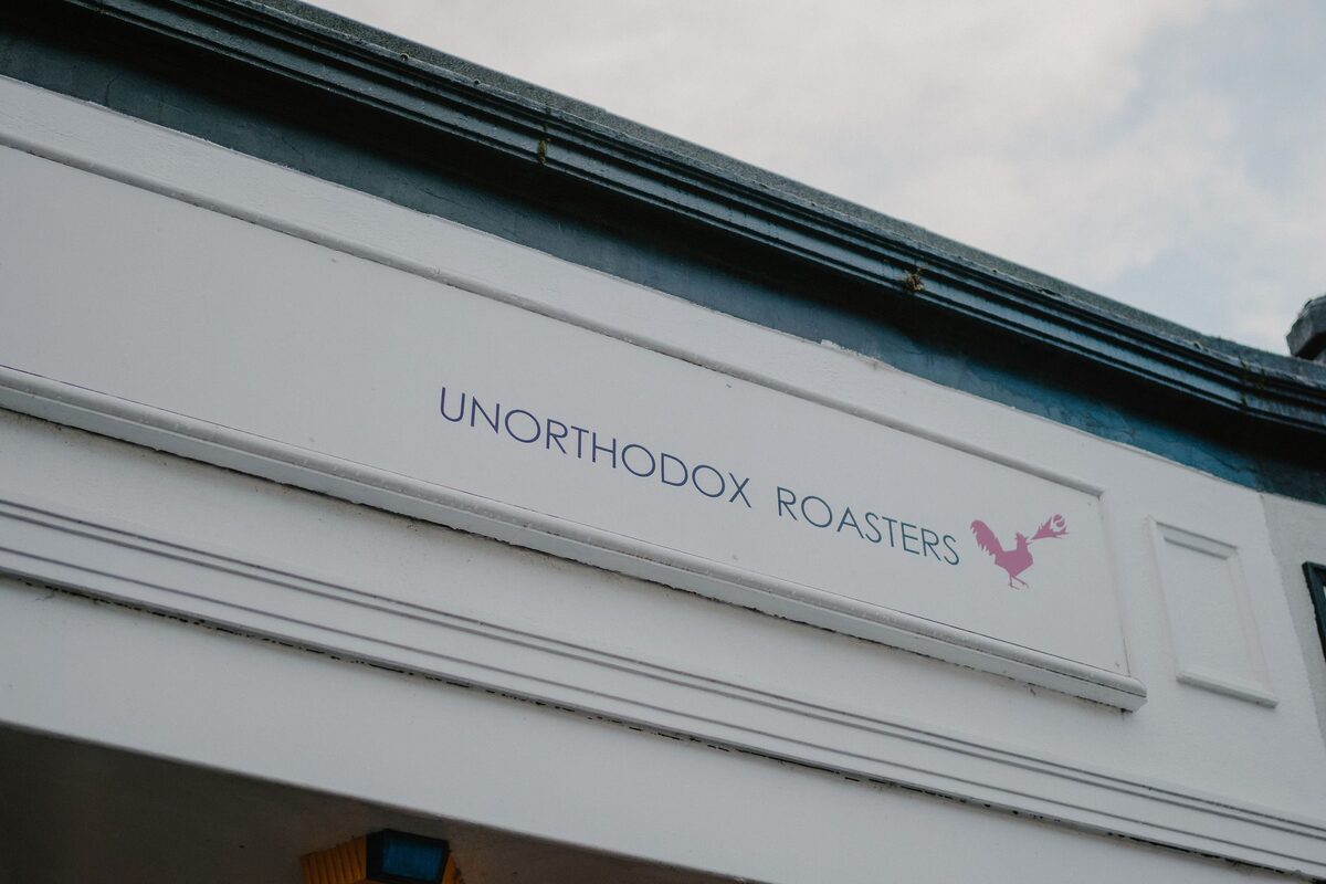 Shopfront sign reading "Unorthodox Roasters" with a pink bird logo