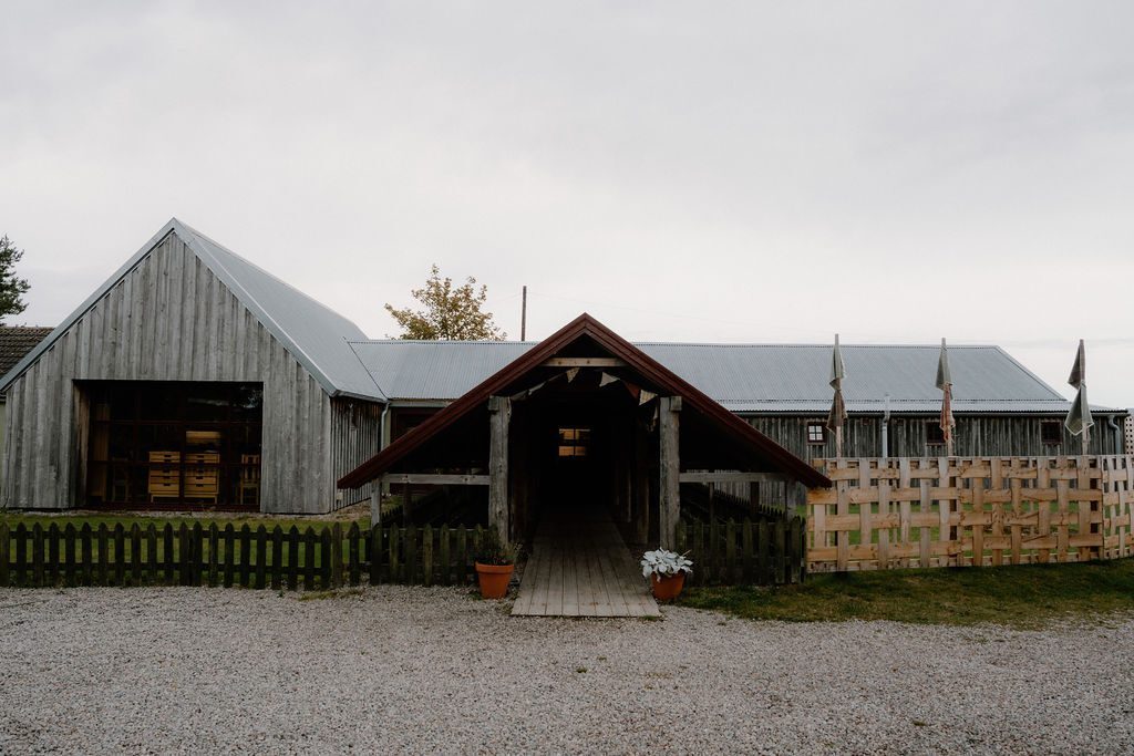 Timber-clad barn buildings with covered walkway and coloured flags along the roofline