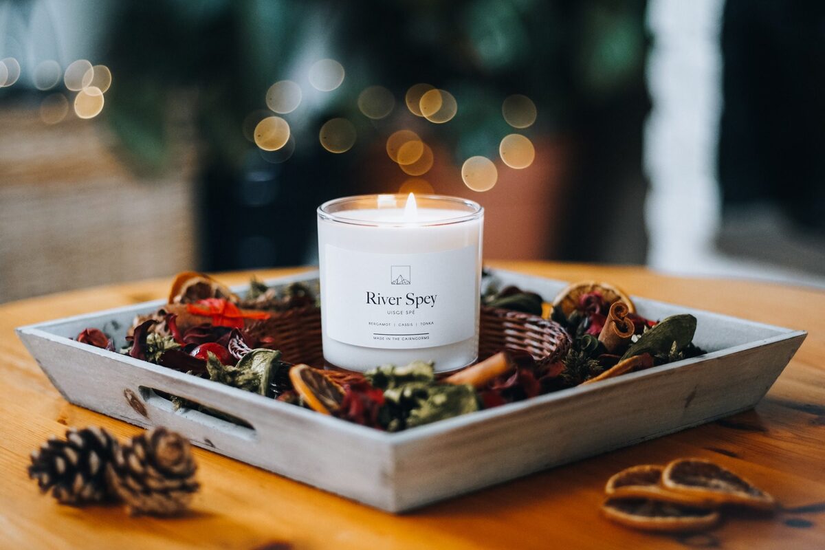 A candle lit among pine cones.