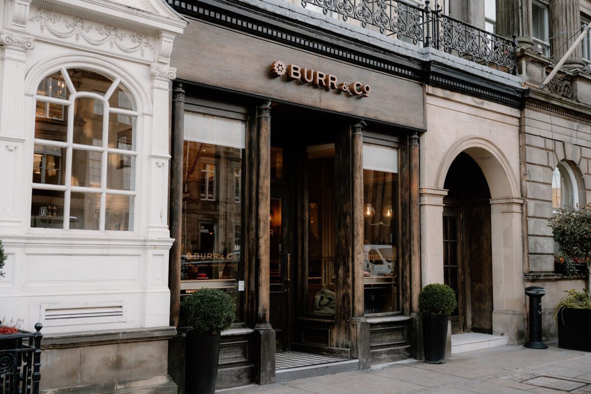 Burr & Co shopfront with wooden entrance and potted topiary trees