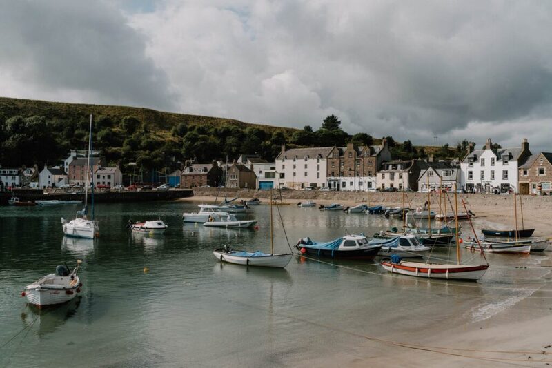 Small boats moored in Stonehaven harbour beneath rows of white waterfront houses