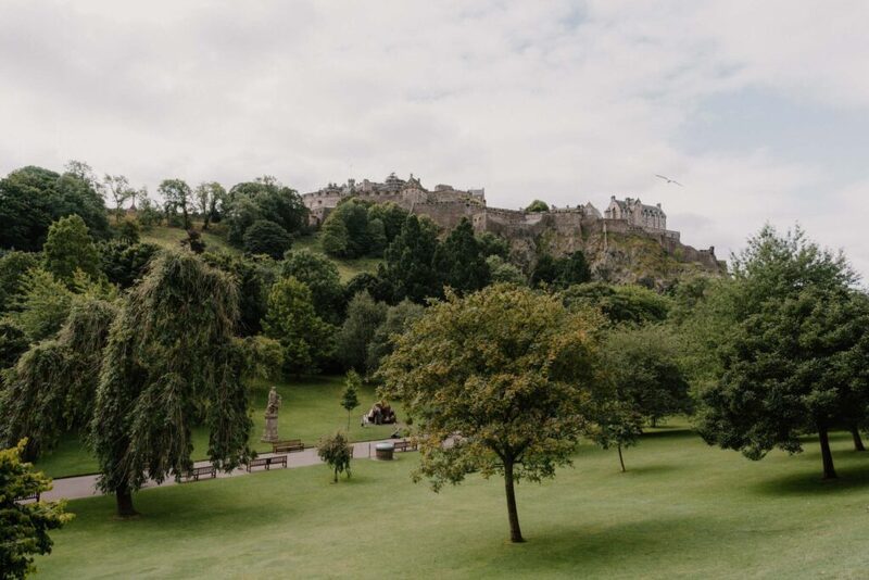 Edinburgh Castle rises above trees and lawns of Princes Street Gardens