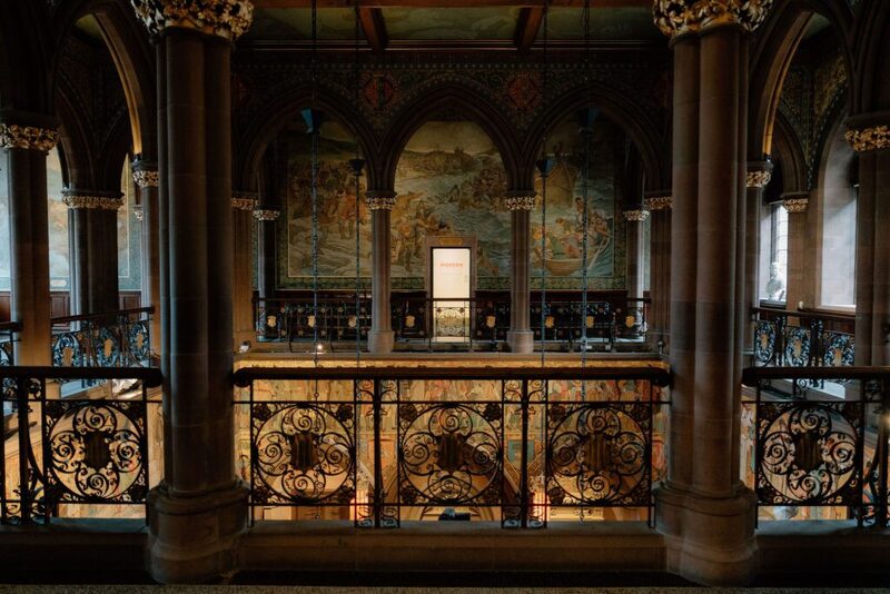 Ornate ironwork balcony beneath painted murals and gothic stone arches