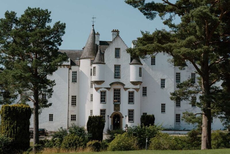 White turreted castle with stepped gables, framed by tall pine trees