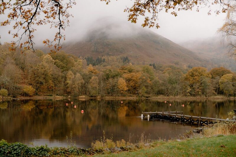 Wooden jetty on a misty loch surrounded by autumn woodland