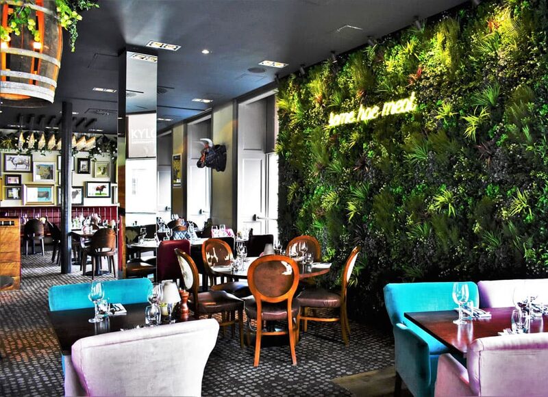 Restaurant interior with a living plant wall reading "beer, hae, meat