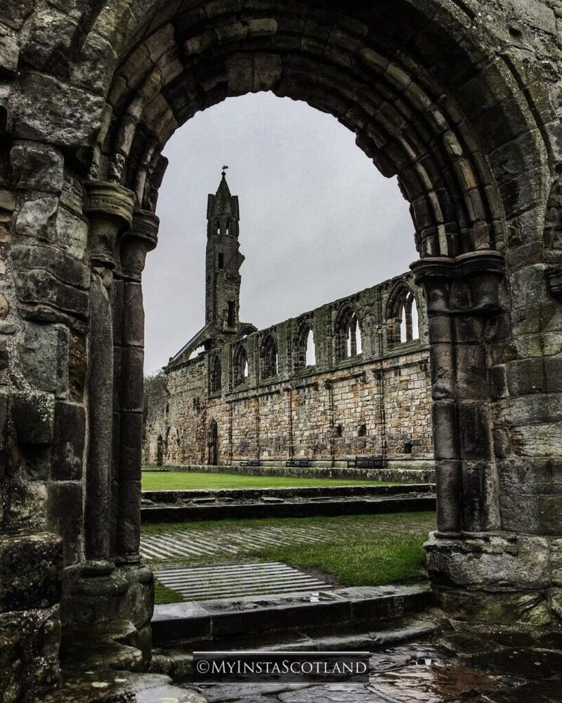 Stone archway framing the ruined tower and walls of St Andrews Cathedral