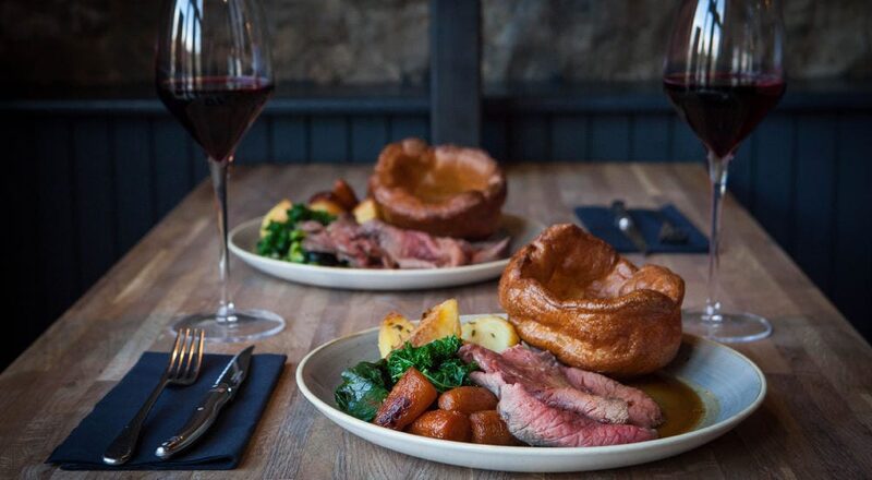Roast beef with Yorkshire pudding and red wine on a wooden table