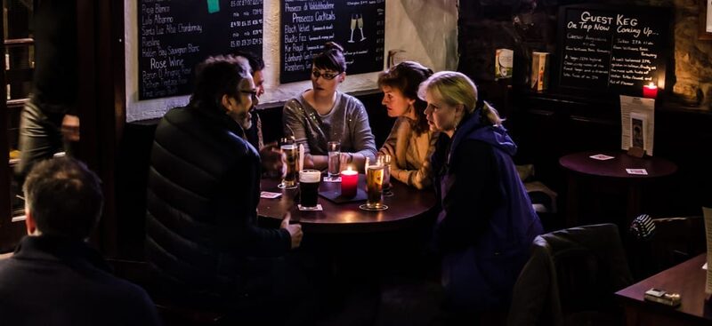 Friends chat round a candlelit table beneath a "Guest Keg" chalkboard menu
