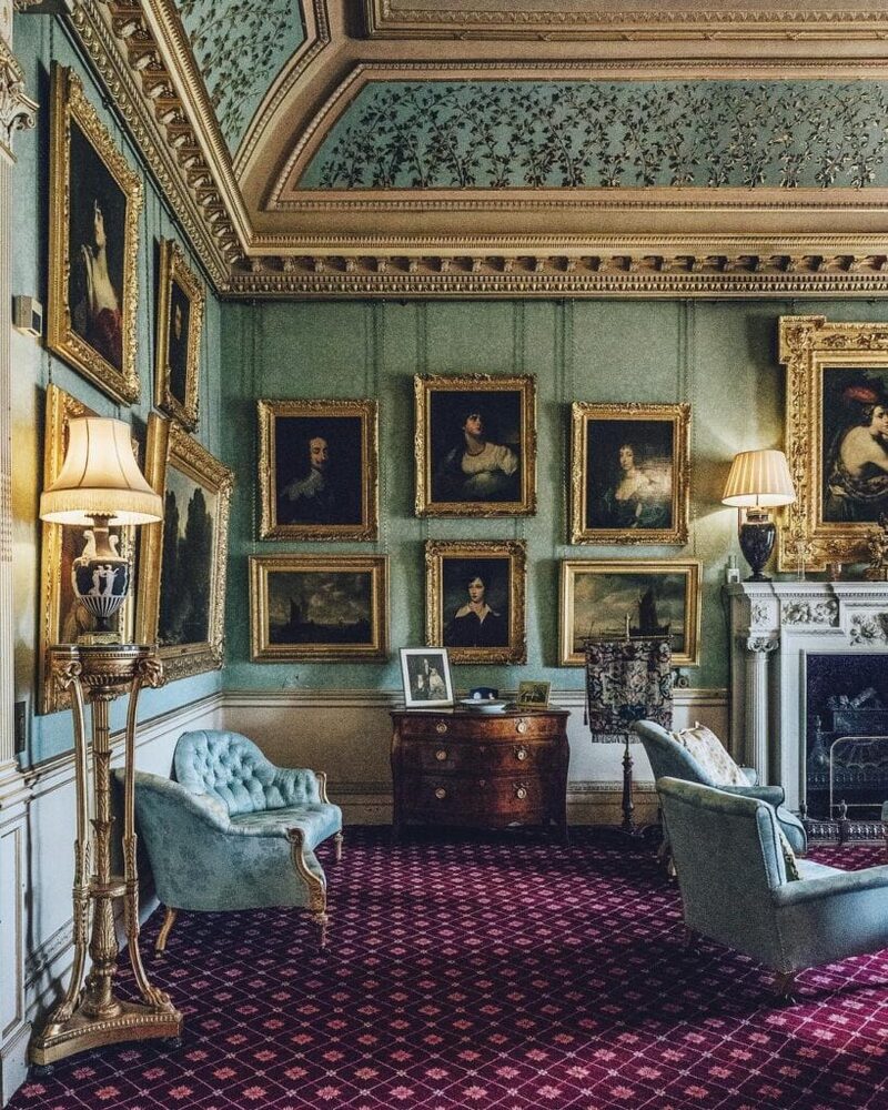 A drawing room at Haddo House, its ornate ceiling above portraits and blue chairs.