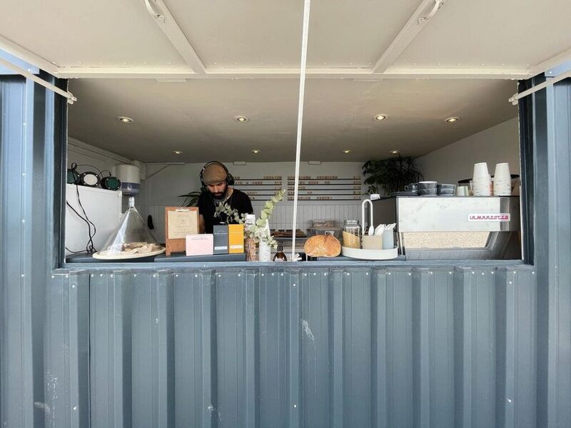Barista serving from a corrugated steel shipping container coffee stand