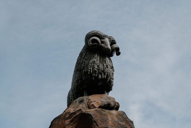 Bronze ram statue with curled horns, mounted on a stone plinth