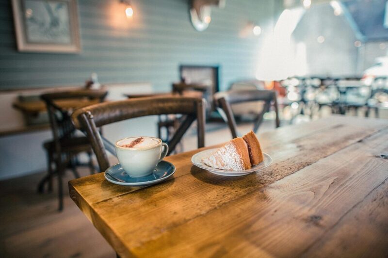 Cappuccino and sliced cake on a wooden table in a café