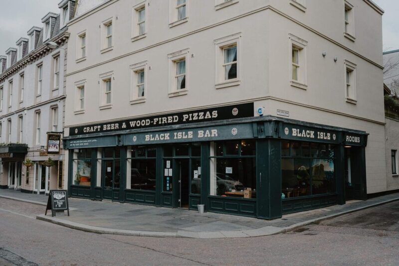 Corner building with green shopfront reading "Black Isle Bar, Craft Beer & Wood-Fired Pizzas