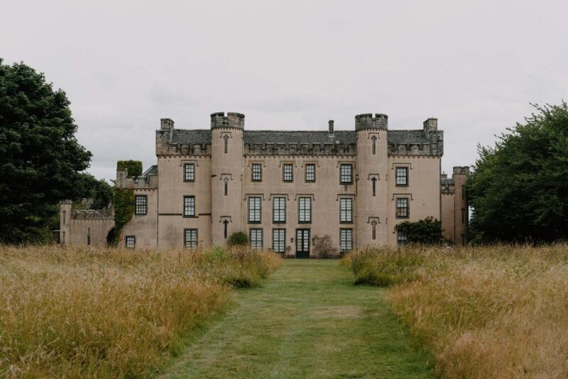 Turreted castle with rows of tall windows behind a mown grass path
