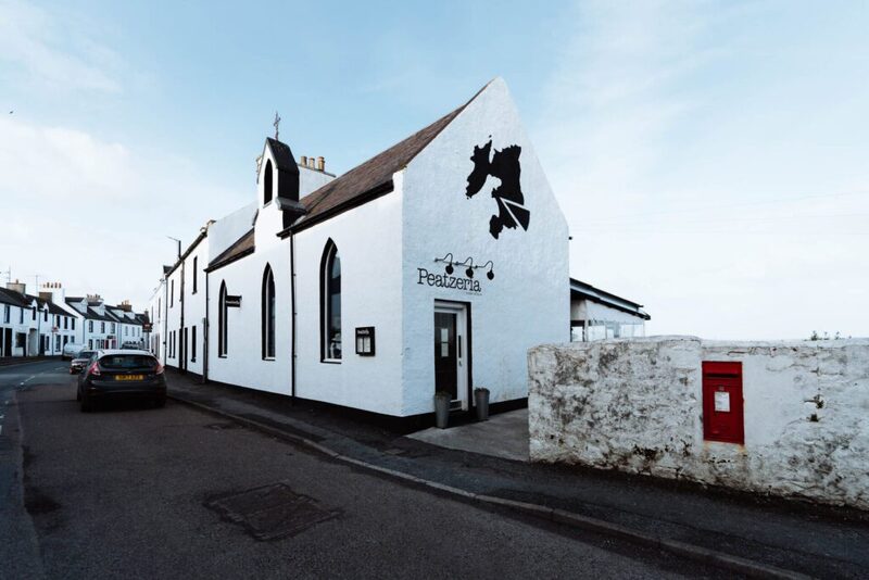 Peatzeria's whitewashed building on Shore Street, Bowmore, with its belfry and pointed windows.