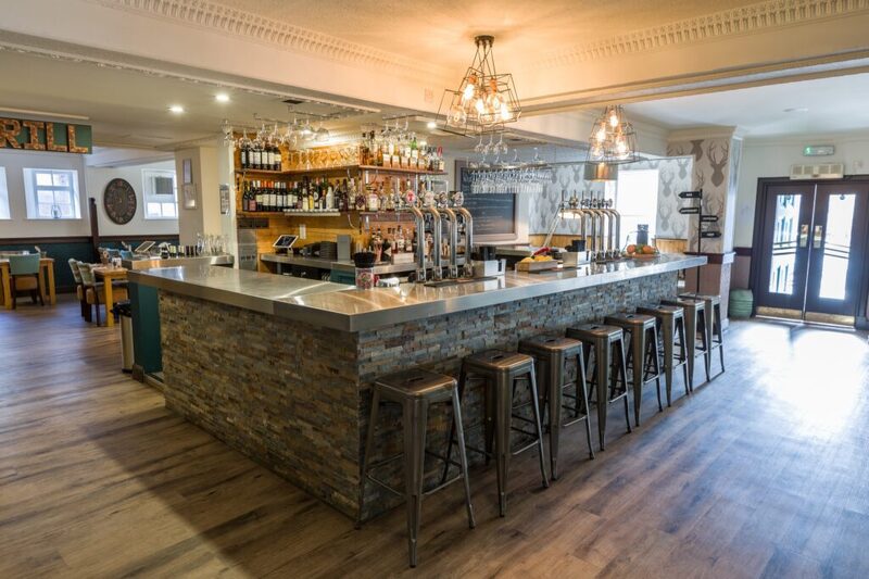 Stone-clad bar with metal stools, beer taps and chandeliers overhead