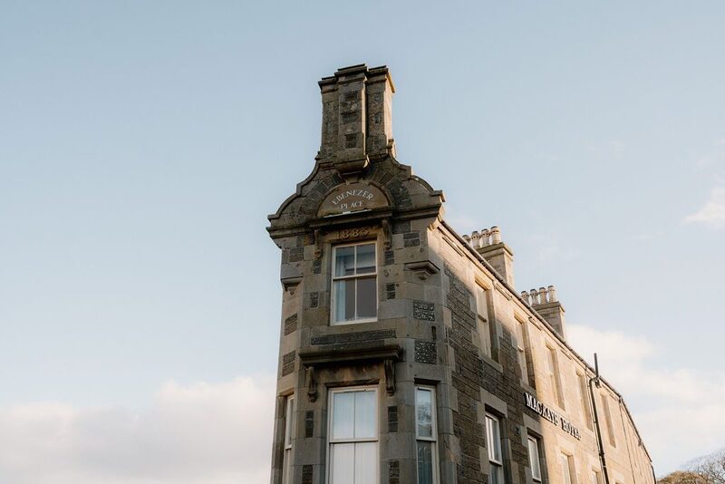 Sandstone corner building with tall chimney stacks against clear sky
