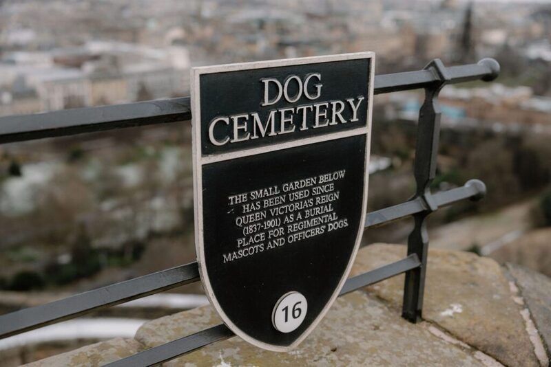Dog Cemetery plaque on railings overlooking Edinburgh's rooftops from the castle wall