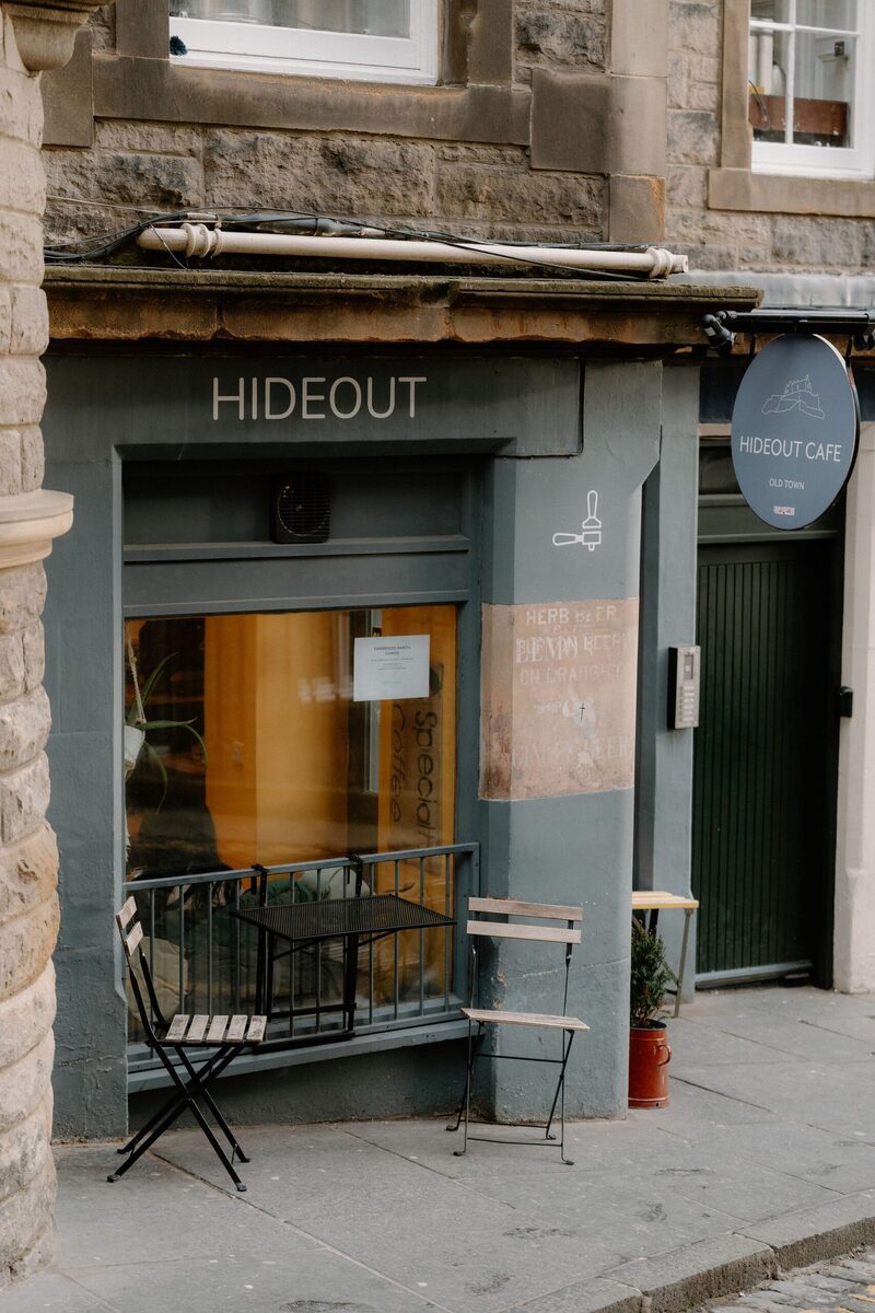 Hideout Cafe frontage with folding chairs beside its shuttered window