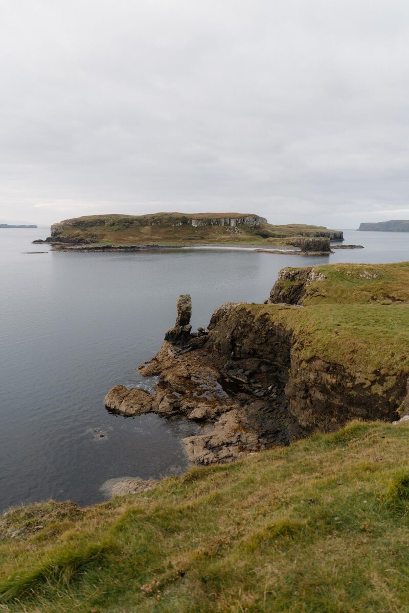 Grassy sea cliffs and a rock stack overlooking a flat-topped island